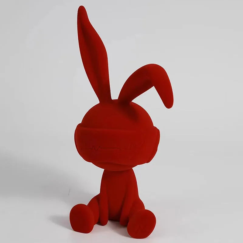 Green resin rabbit table ornament with suede blindfold on wooden surface