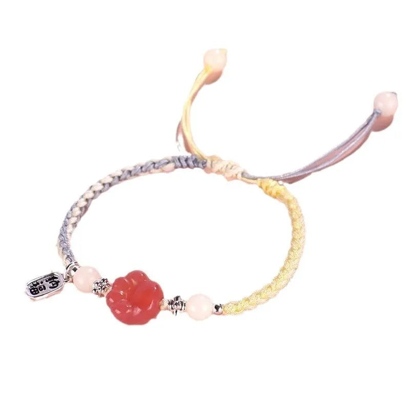 Red cat's paw glass bead on a handmade pink woven bracelet for couples.
