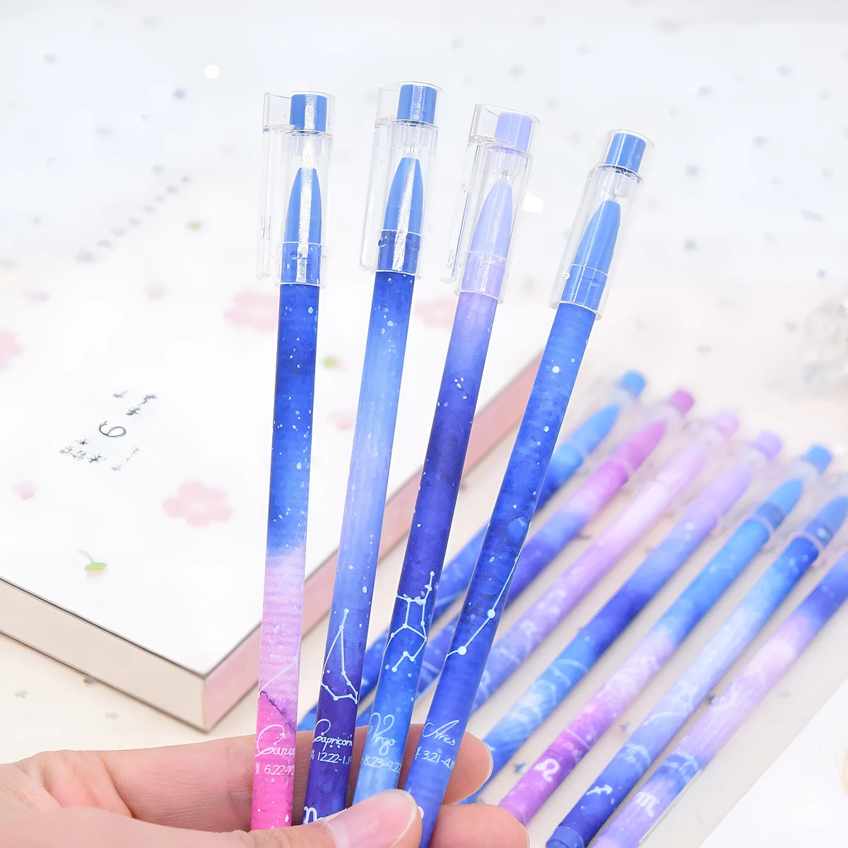 Box of 12 plastic gel pens with quick-drying ink and constellation-themed designs in assorted colours