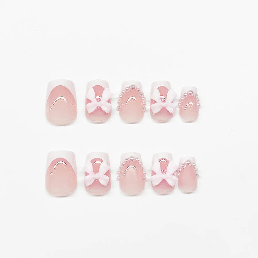 Artificial press-on nails with French manicure style showing bow patterns and tulip designs on short European square nails