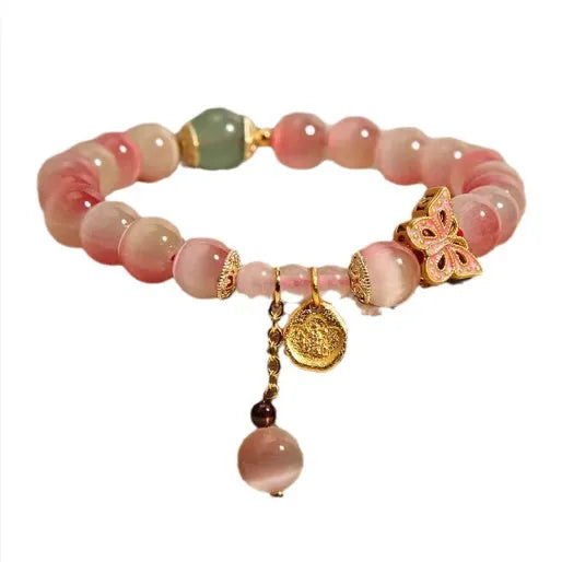 Close-up of a women's bracelet with a pink opal butterfly charm on an electroplated chain.