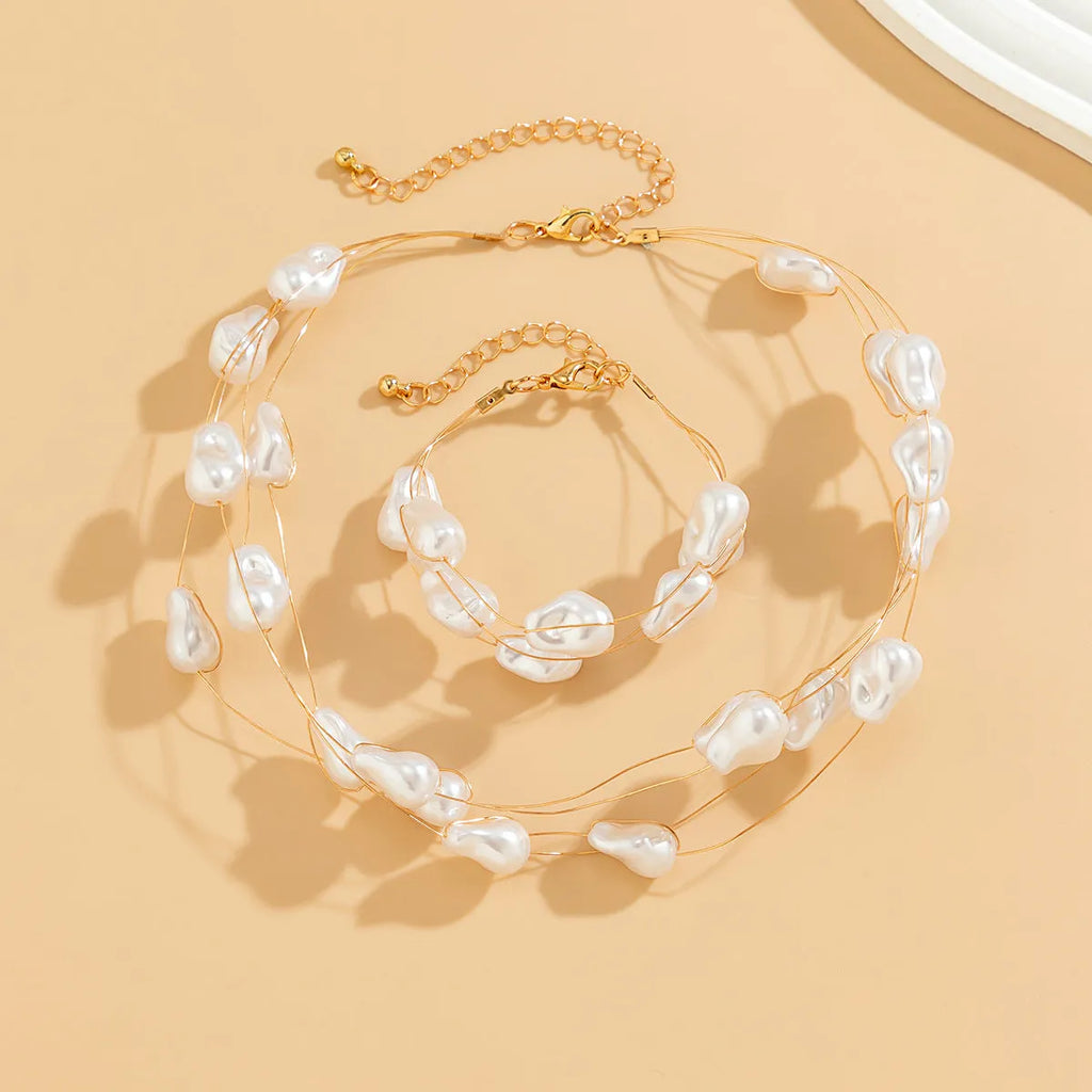 Gold-tone baroque imitation pearl necklace and bracelet set with U-shaped pendant on woman