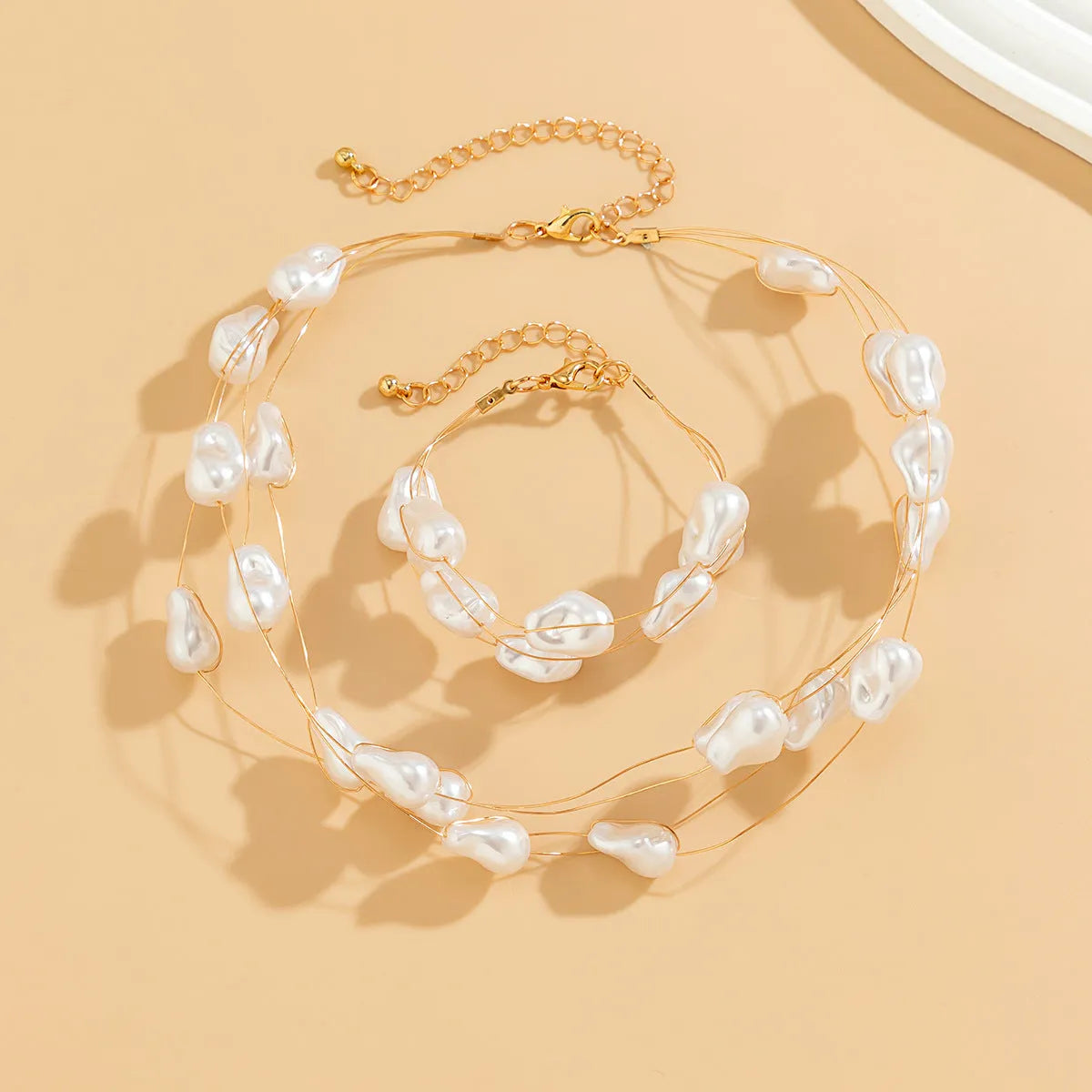 Gold-tone baroque imitation pearl necklace and bracelet set with U-shaped pendant on woman