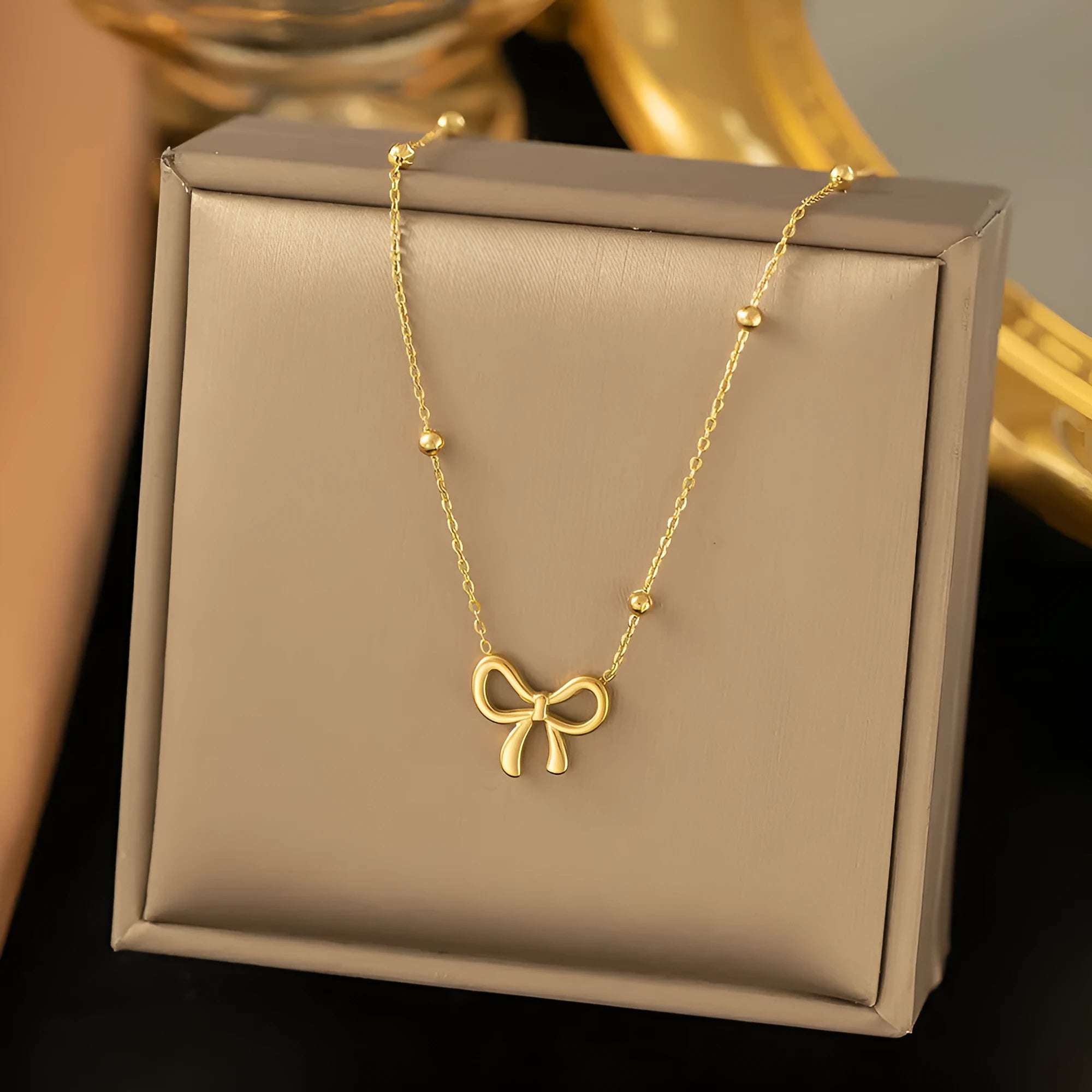 Gold bow necklace with adjustable chain on titanium steel with electroplated finish