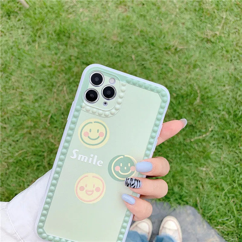 Green TPU iPhone back cover case with geometric smiley face and polka dot frame pattern.