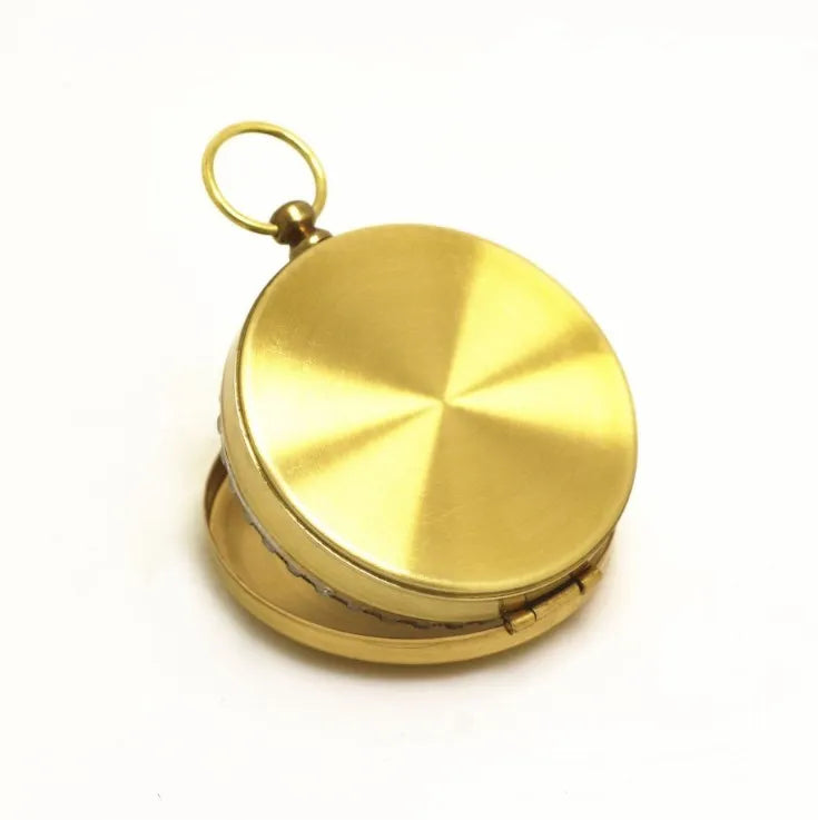 Gold metal flip compass with open lid showing compass face, pocket watch style