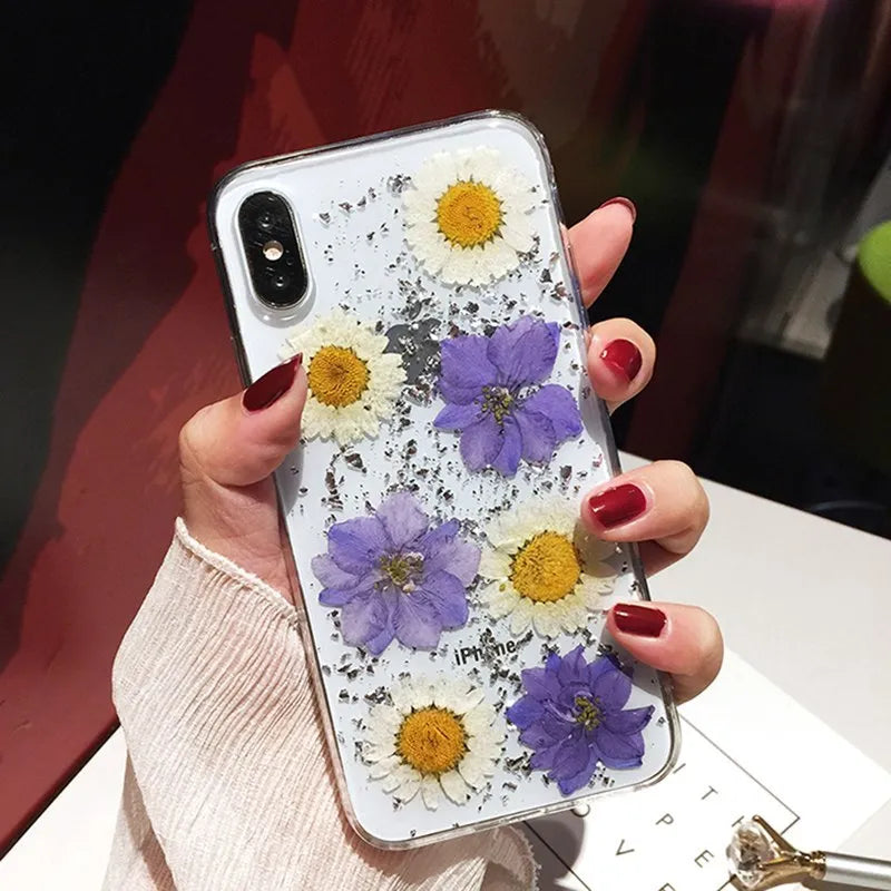 Clear soft TPU iPhone case with pink dried flowers preserved in epoxy resin on the back.