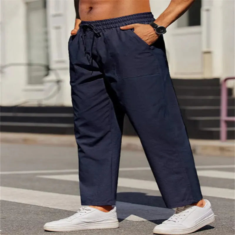Men's straight-leg linen trousers in a solid colour, showing the elasticated mid waist and long leg.