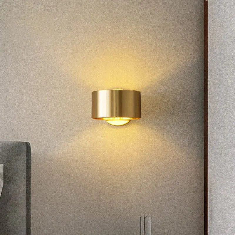Modern minimalist copper wall lamp in gold finish mounted on a wall.