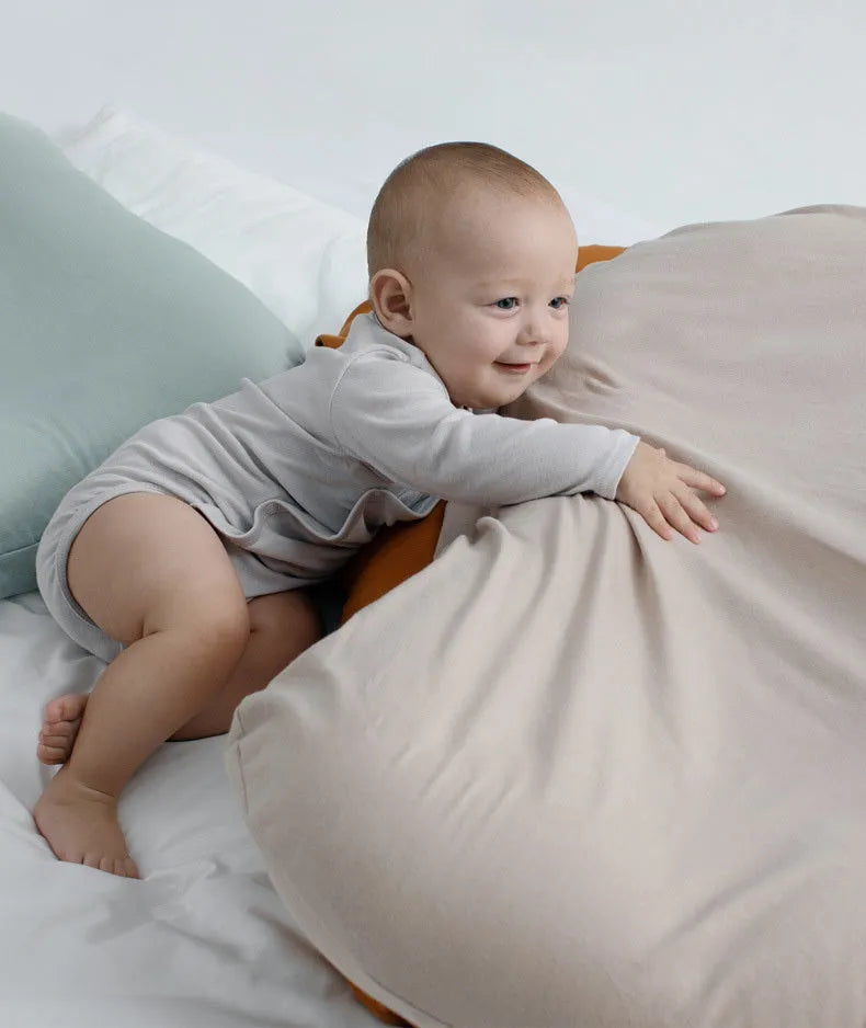 Cotton portable baby nest crib for newborns, beige colour, shown on a bed.