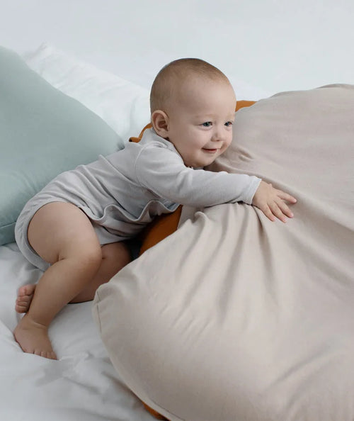 Cotton portable baby nest crib for newborns, beige colour, shown on a bed.