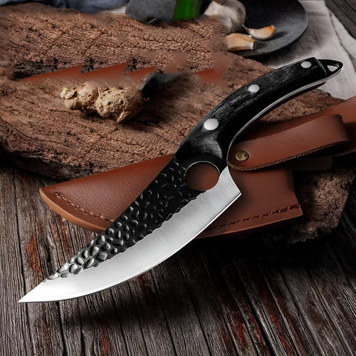 Curved boning butcher knife with hammer-pattern blade and brown leather sheath on a cutting board.