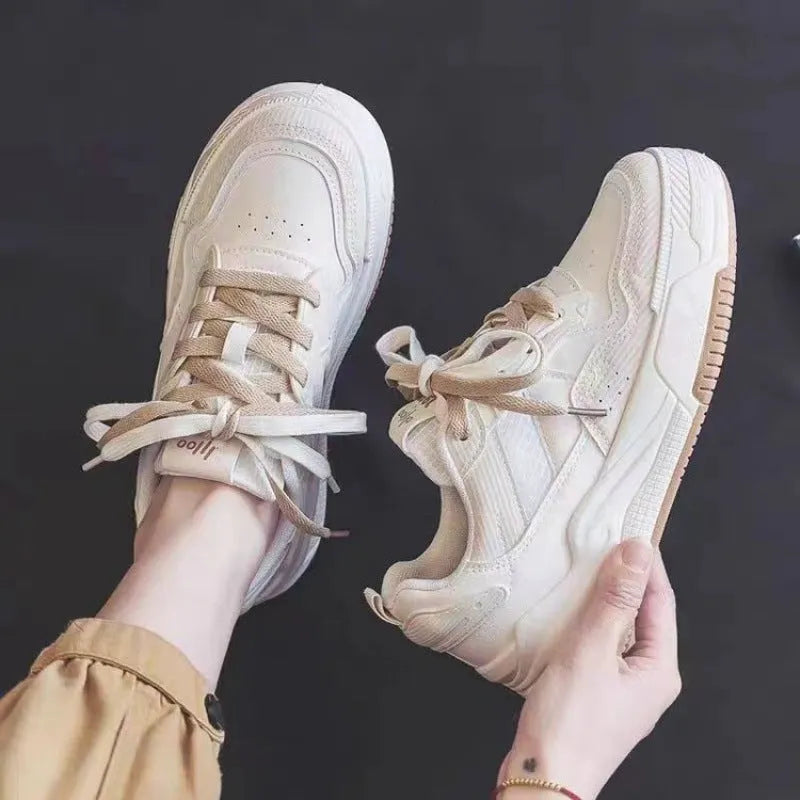 Women's pink and white low-top sneakers with a height-increasing rubber sole on a neutral background.