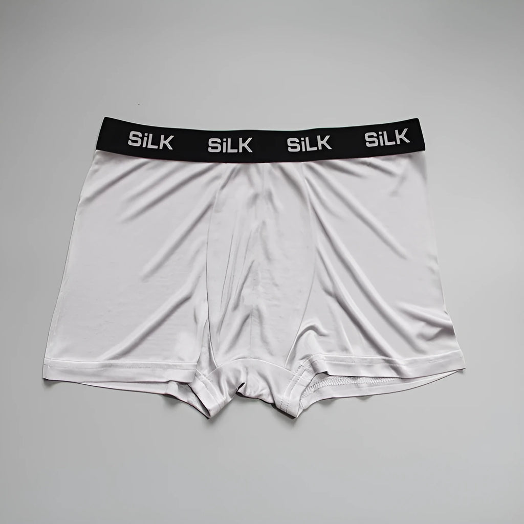 Men's loose-fitting silk shorts in navy blue, shown in a casual setting.