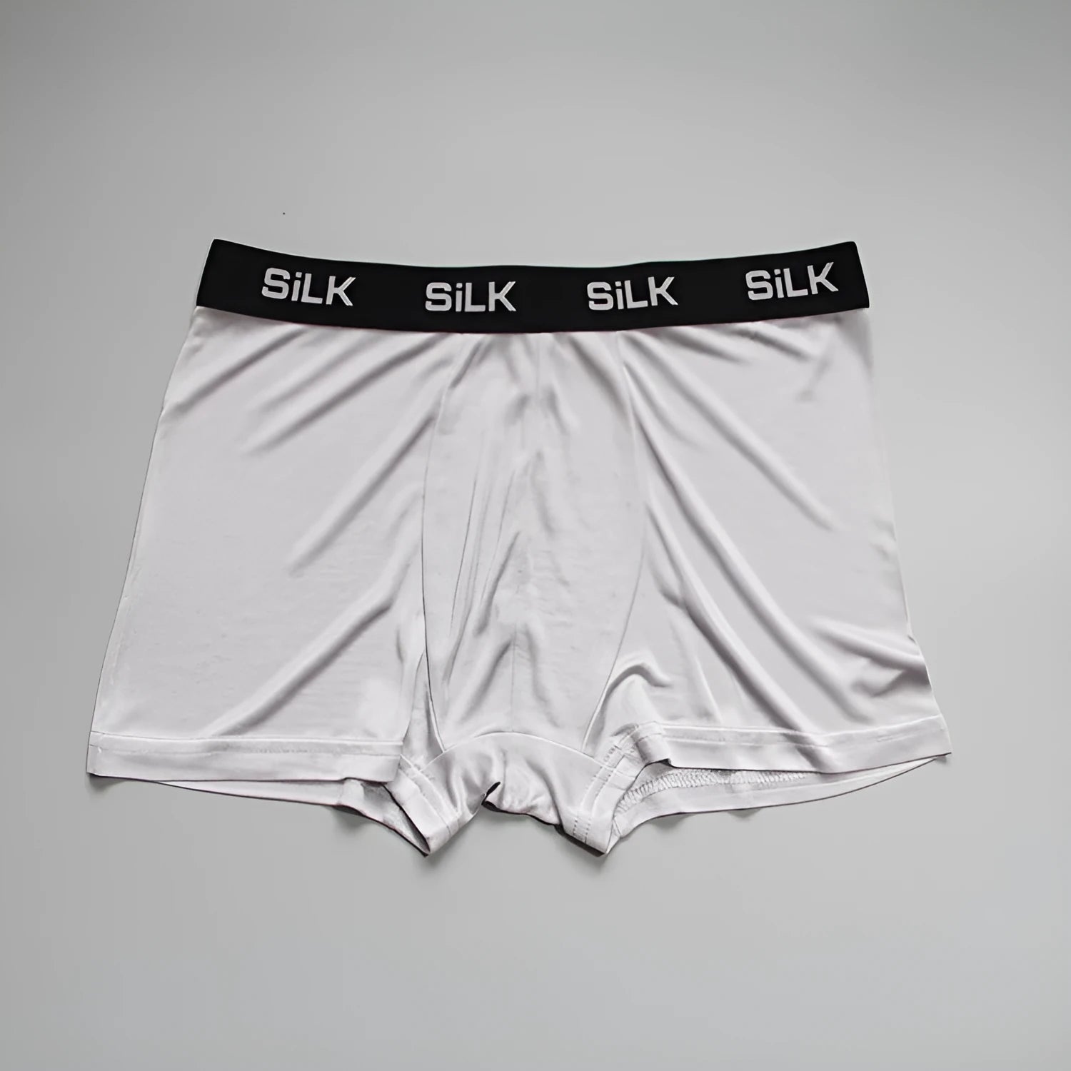 Men's loose-fitting silk shorts in navy blue, shown in a casual setting.