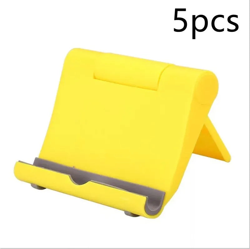 Black PE folding stand holding a smartphone at an angle on a wooden table.