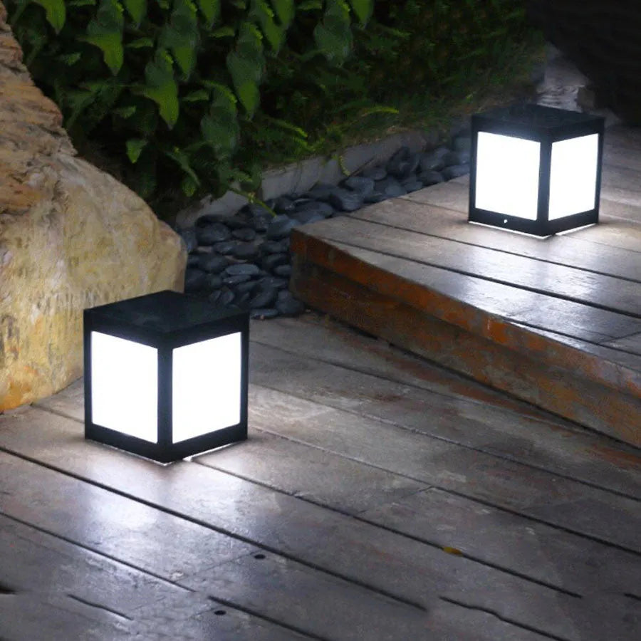 A set of waterproof solar-powered garden lights installed along a lawn edge and wall.