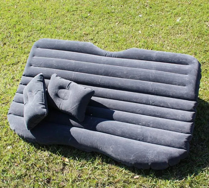 Inflatable car bed with flocked surface folded beside two pillows in storage bag for vehicle sleeping