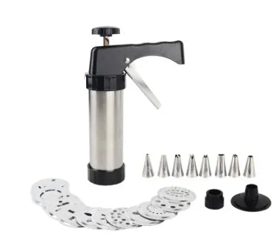 Stainless steel biscuit press gun with assorted cookie mould discs and icing nozzles on a baking tray.