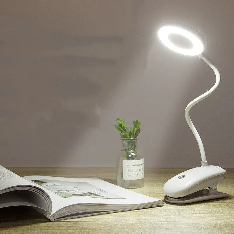 Modern clip-on rechargeable desk lamp with a white plastic shade and touch controls on its base.