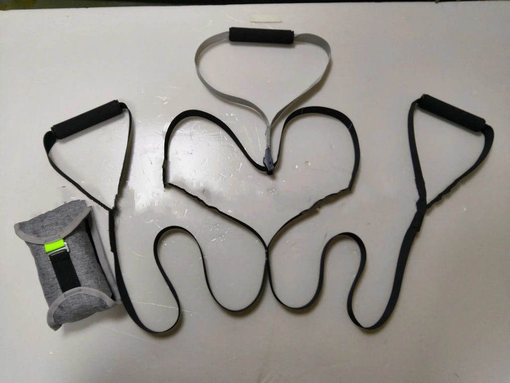 Black suspension training belt with nylon webbing and metal climbing hook on a gym floor