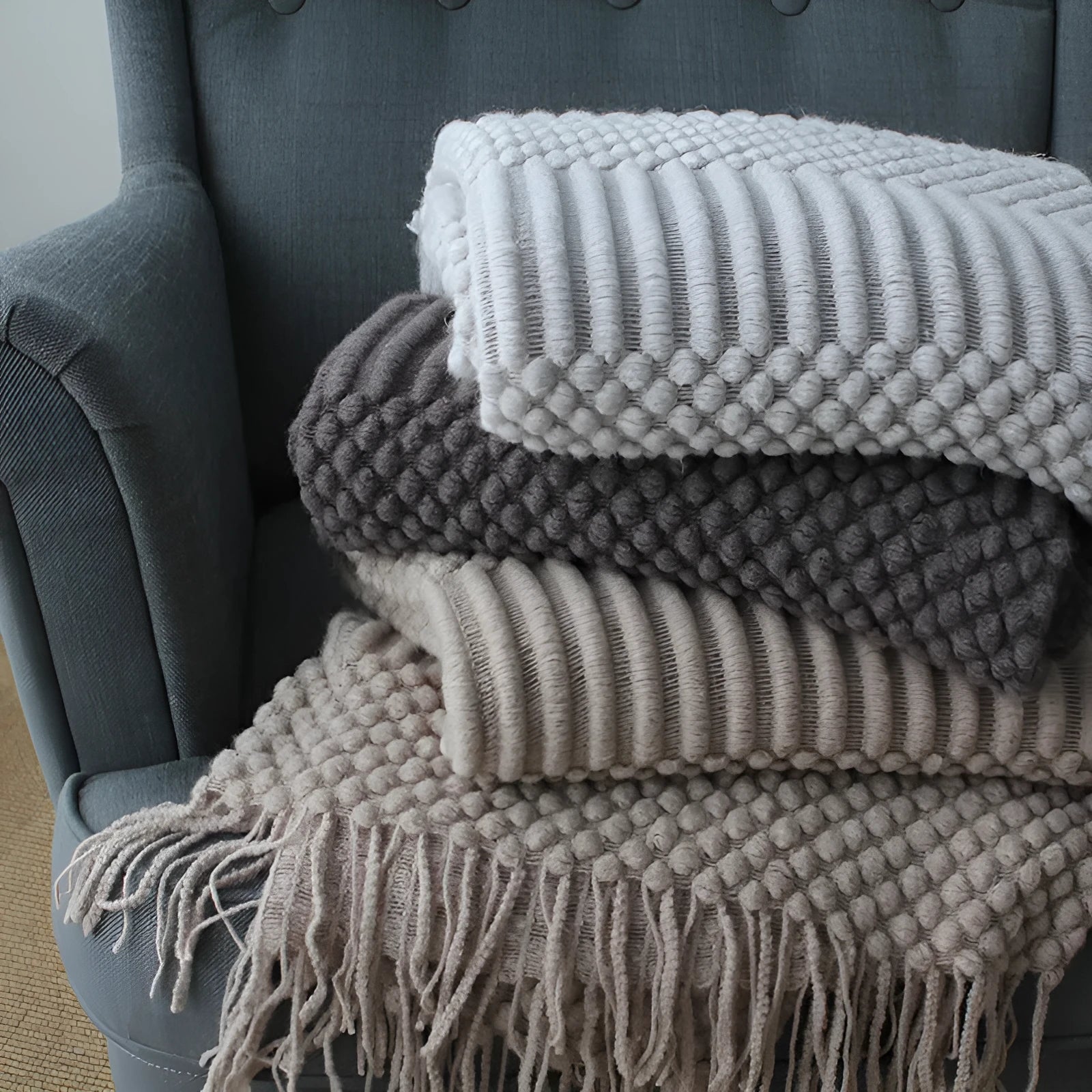 Small rectangular nap blanket in a neutral colour, showing its compact size relative to a hand.