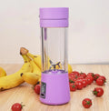 Pink mini USB electric fruit juicer with carrying rope on a kitchen countertop.
