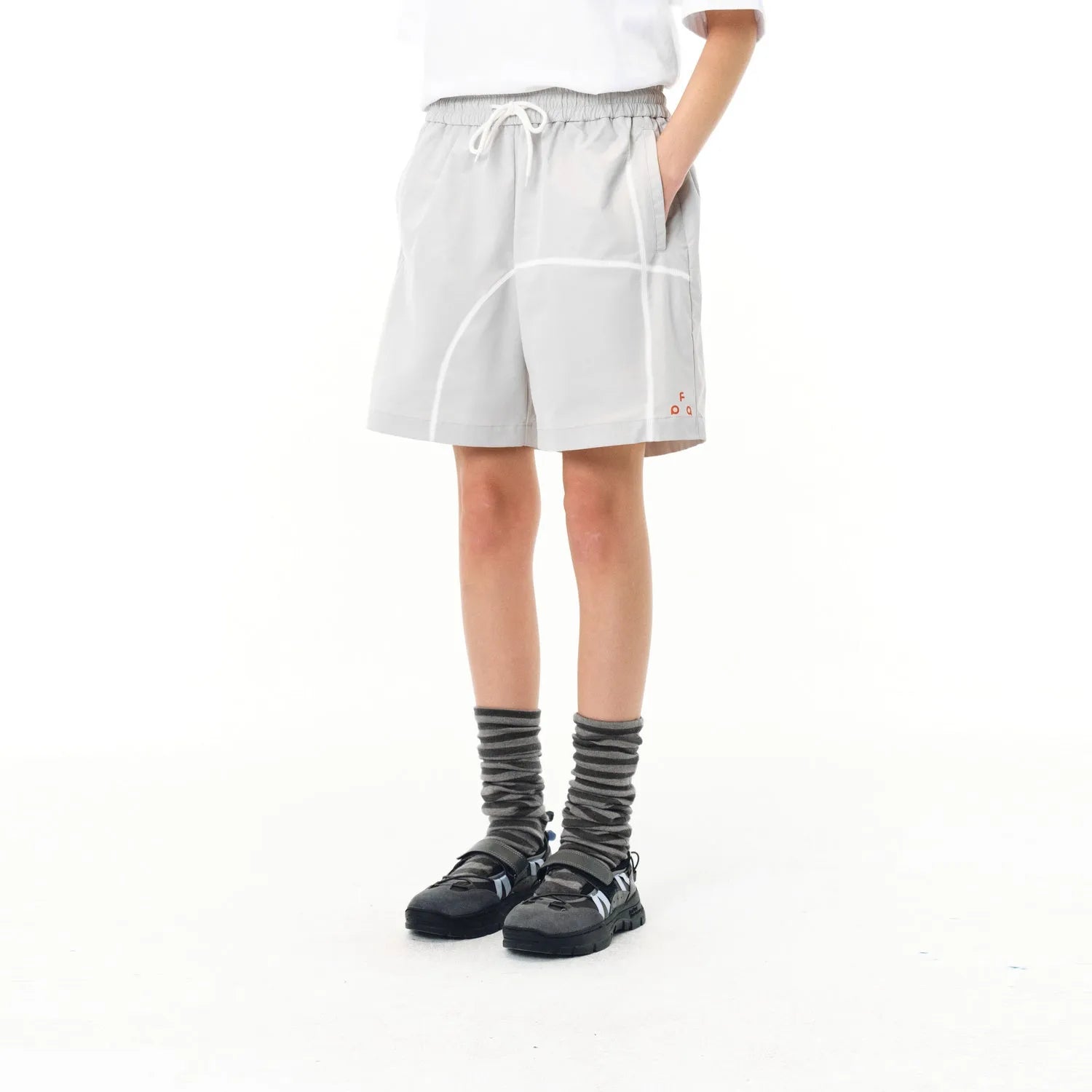 Man wearing retro-style light-coloured drawstring shorts with a loose fit, on a beach.