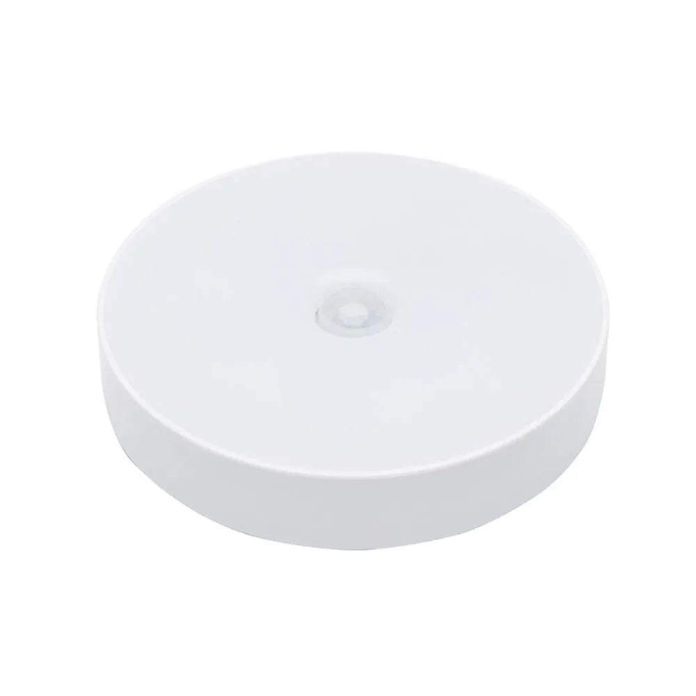 Small white round USB rechargeable motion sensor LED night light with adhesive backing.