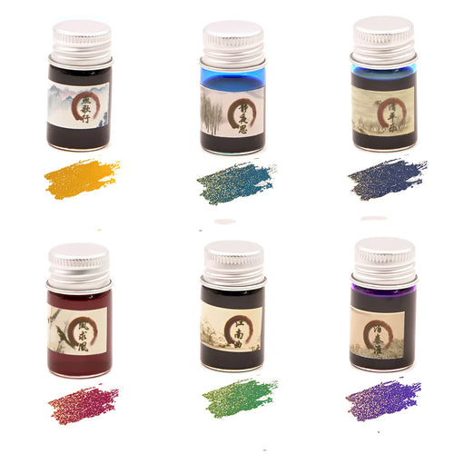 Set of six small glass bottles of pastel antiquity ink with gold powder for dipping pens.