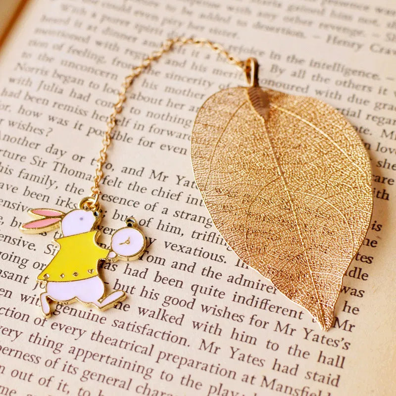 Metal leaf-shaped bookmark with a choice of Alice, rabbit, or clock charm designs on kraft card.