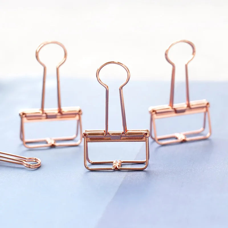 Rose gold metal ring binder set with small and large folders for documents on a desk