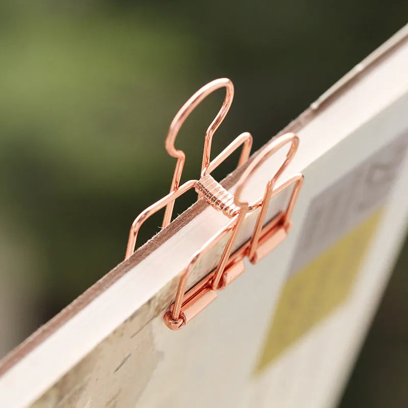 Rose gold metal ring binder set with small and large folders for documents on a desk