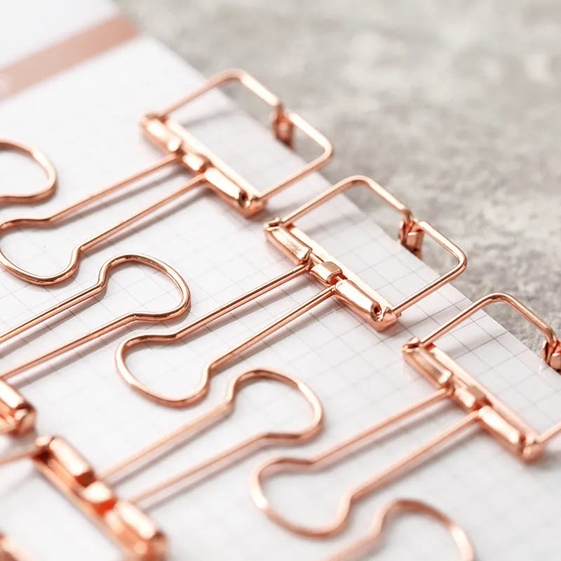 Rose gold metal ring binder set with small and large folders for documents on a desk