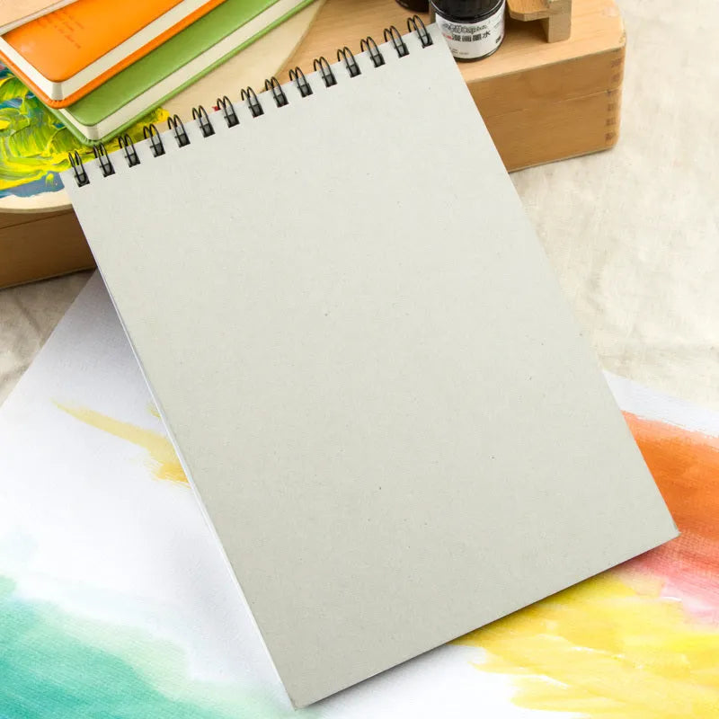 Green spiral-bound water soluble colour lead sketchbook open flat, showing thin paper suitable for pencil and wash techniques.