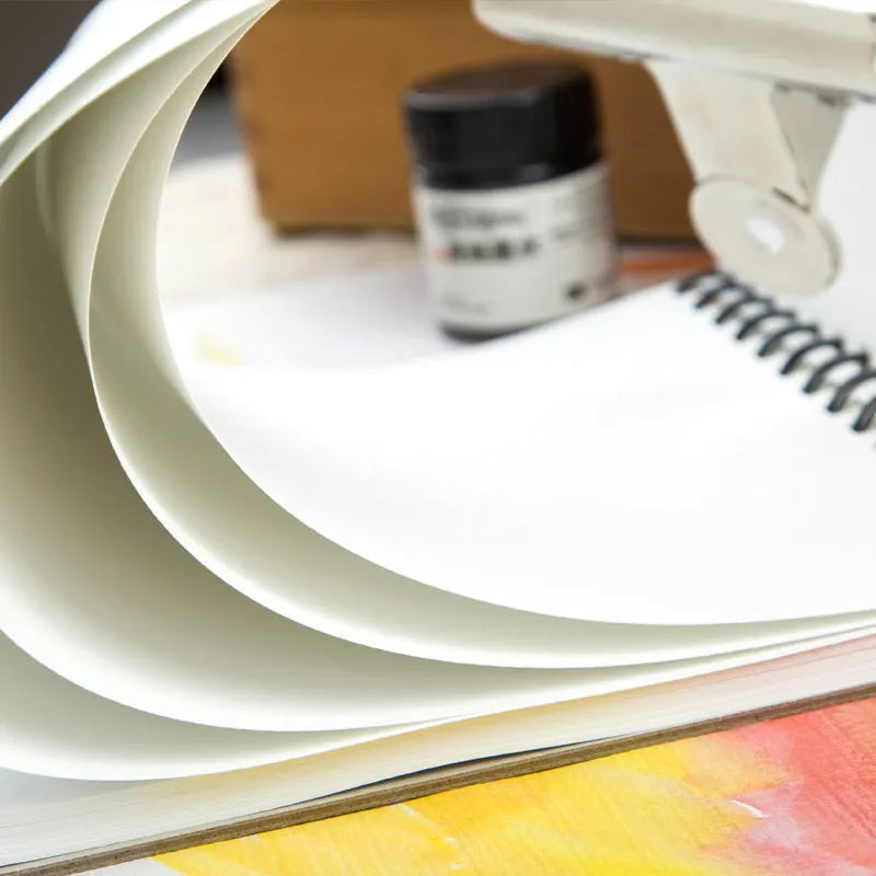Green spiral-bound water soluble colour lead sketchbook open flat, showing thin paper suitable for pencil and wash techniques.