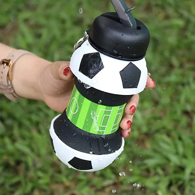 White collapsible soccer ball silicone water bottle with straw and black carrying clip on white background