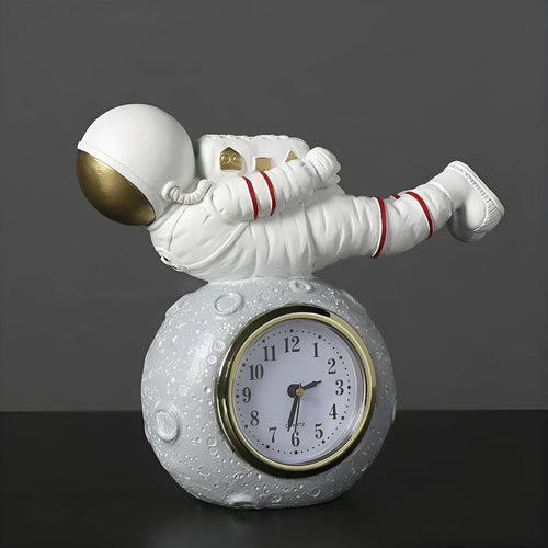 Astronaut resin clock trinket decoration in gold finish on a wooden desk with a bookshelf in background