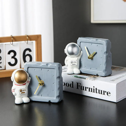 Astronaut resin clock trinket decoration in gold finish on a wooden desk with a bookshelf in background