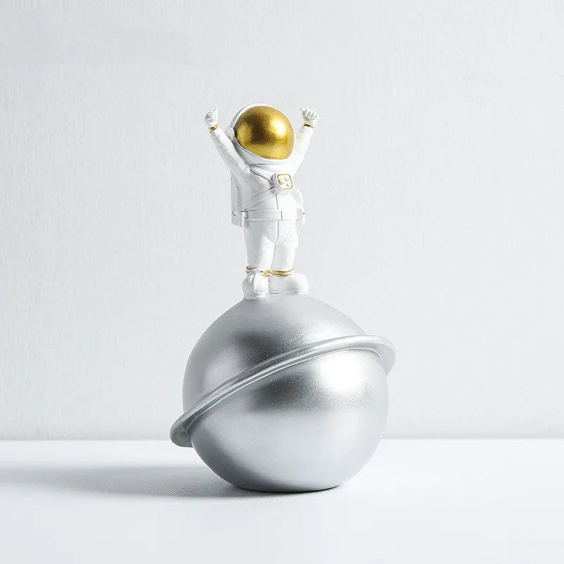 Astronaut resin clock trinket decoration in gold finish on a wooden desk with a bookshelf in background