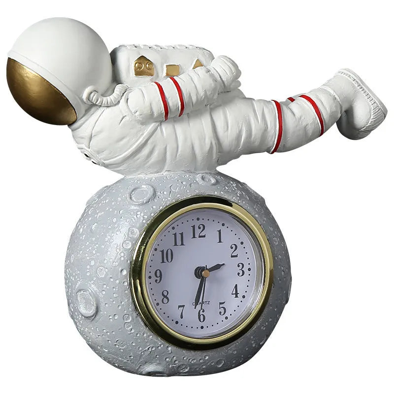 Astronaut resin clock trinket decoration in gold finish on a wooden desk with a bookshelf in background