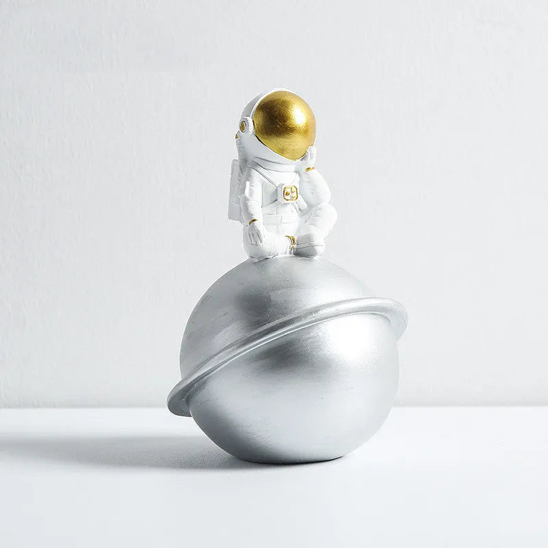 Astronaut resin clock trinket decoration in gold finish on a wooden desk with a bookshelf in background