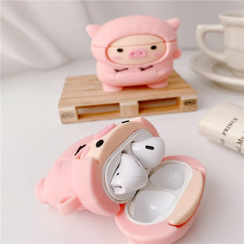 Rose pink silicone AirPods case cover with a cartoon pig in a sweater design and a silver keychain hook.