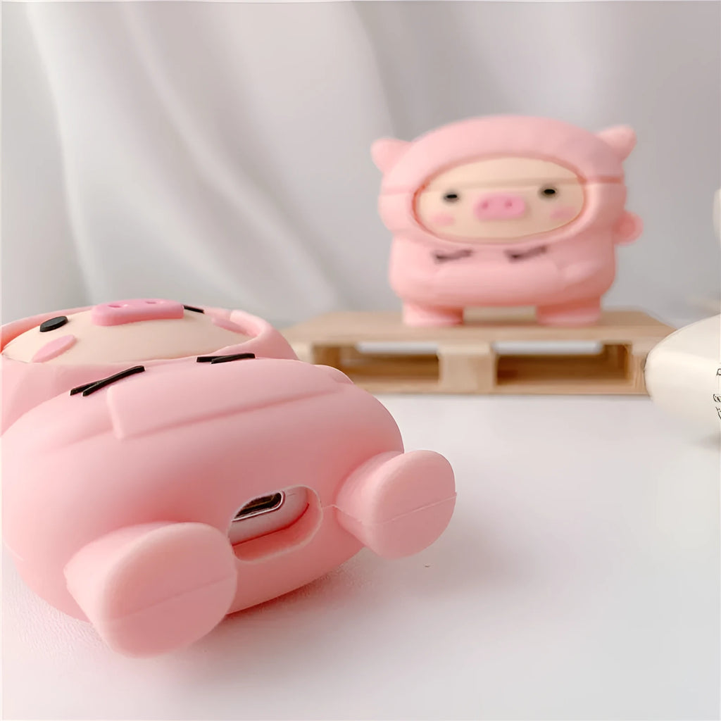 Rose pink silicone AirPods case cover with a cartoon pig in a sweater design and a silver keychain hook.