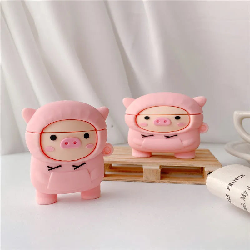 Rose pink silicone AirPods case cover with a cartoon pig in a sweater design and a silver keychain hook.