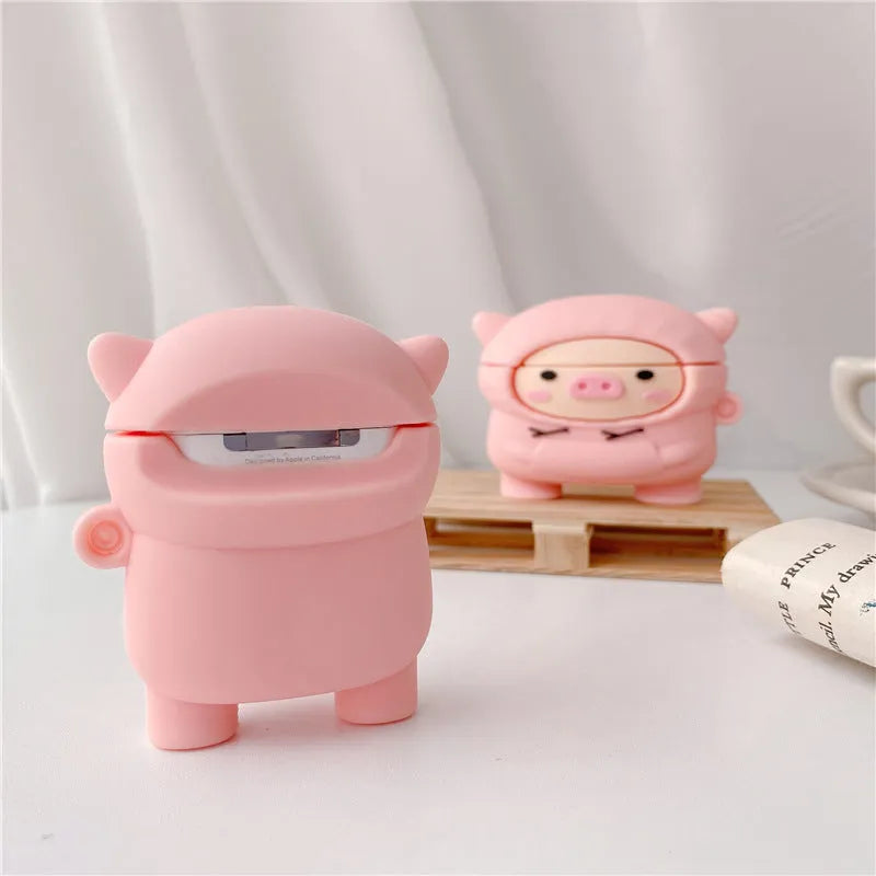 Rose pink silicone AirPods case cover with a cartoon pig in a sweater design and a silver keychain hook.