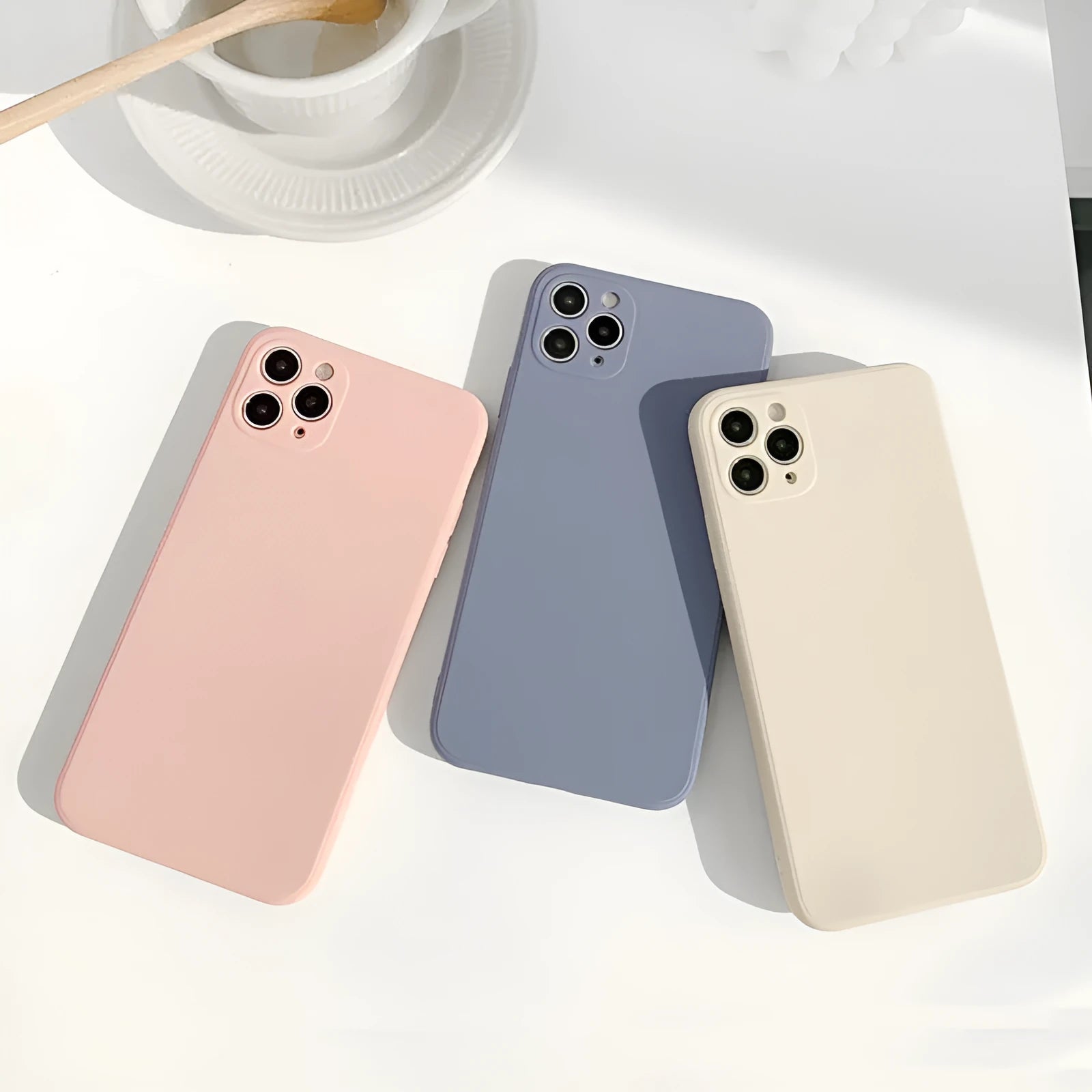 Simple solid colour silicone iPhone case in powder, slate blue or antique white on an iPhone.