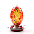 Glass hummingbird feeder with four feeding ports, perches, and anti-ant hook in stained-glass pattern