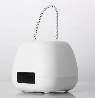 White rechargeable baby night light with remote control and projection function on a bedside table