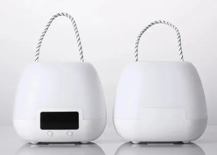 White rechargeable baby night light with remote control and projection function on a bedside table